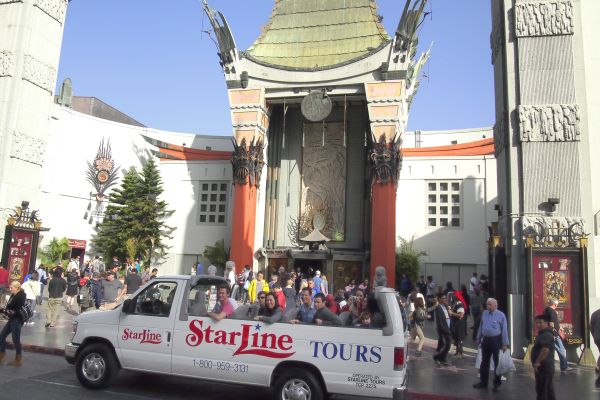smiling Tourists pose for pictures on a Starline van in front of the Chinese theater