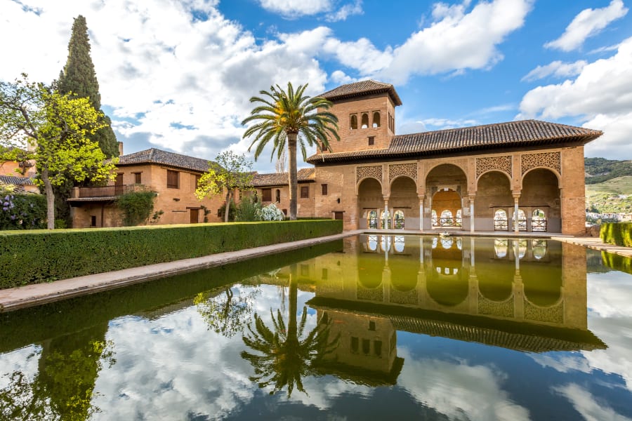 A large central pond faces the arched portico behind which stands the Tower of the Ladies, inside the Alhambra of Granada.jpeg