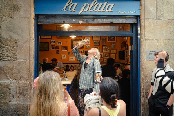 Tourists participating in a traditional drinking ritual in a local Barcelona bar.