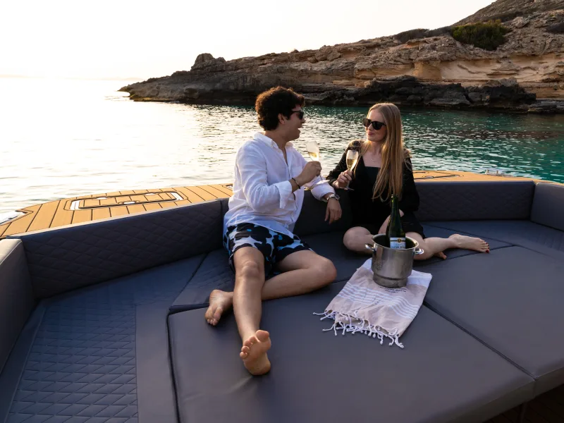 Couple toasting on the bow sundeck at sunset