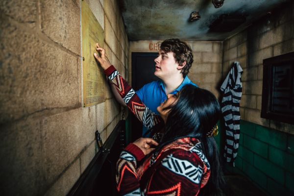 A man and woman view the layout of the prison at the Escape Game