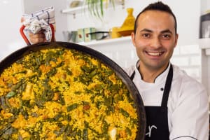 Chef posing with paella during Spanish cooking class
