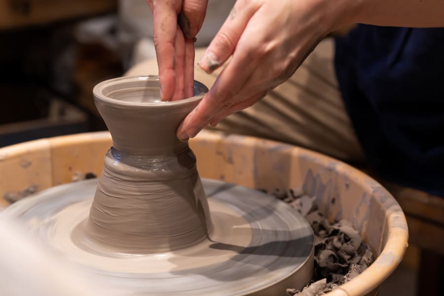 Hands sculpting clay on pottery wheel during Private Pottery and Temple Tour in Japan