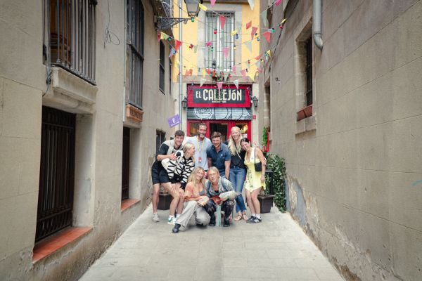 Group of tourists posing for a photo in a narrow alleyway in Barcelona.